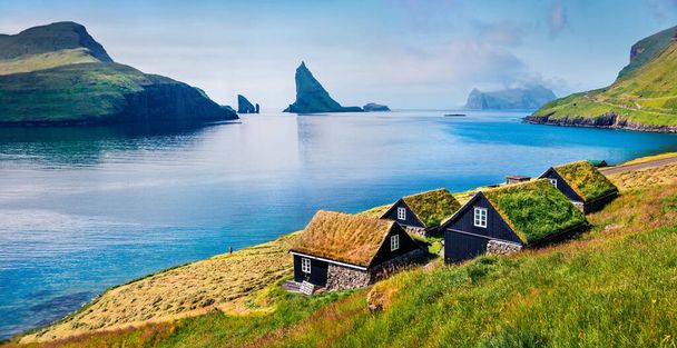 典型的な芝生の上の家と背景にティンダルム崖とバー村の日当たりの良い夏のシーン。バガール島、フェロー諸島、デンマーク、ヨーロッパのパノラマの朝の景色。旅のコンセプト背景 - 写真・画像