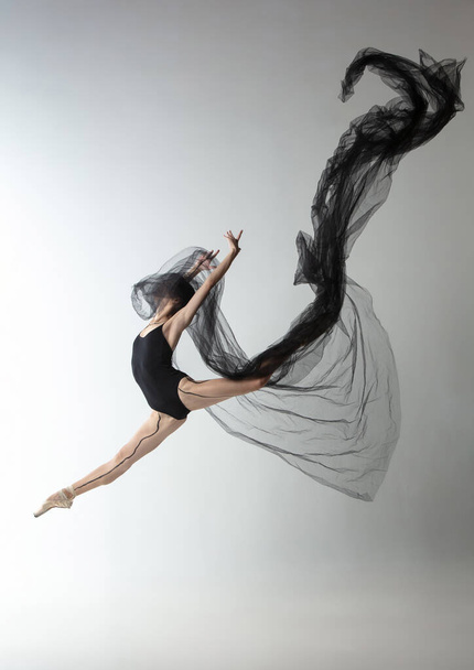 Portrait of young adorable Japanese ballerina dancing with transarent fabric, black cobweb isolated on light gray studio background. Beauty, line art, emotions concept. - Φωτογραφία, εικόνα