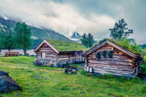 Norwegian typical grass roof wooden old house on the Innerdalsvatna lake. Gloomy morning scene in Norway, Europe. Beauty of countryside concept background. Instagram filter toned - Photo, Image