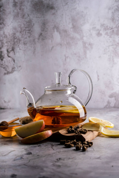 селективный фокус, свежеваренный чай в прозрачном чайнике, с фруктами и свежими ягодами. листовой чай и специи. натюрморт. для рекламы и меню - Фото, изображение