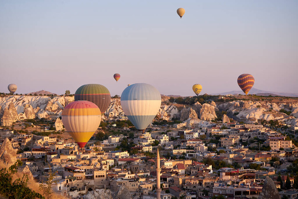 Hot air balloons flying over spectacular Goreme Cappadocia in Turkey view on sunrise. Travel to Turkey concept.A lot of air balloons flying over hills. Turkish tourist sight                          - Photo, image