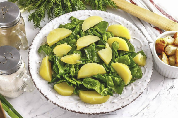 Peel potatoes, rinse and cut into slices. Place on top of spinach. - Fotografie, Obrázek