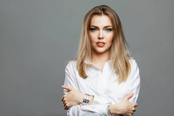 Young woman in a white shirt. Beautiful blonde. Success and confidence. Gray background. - Photo, Image