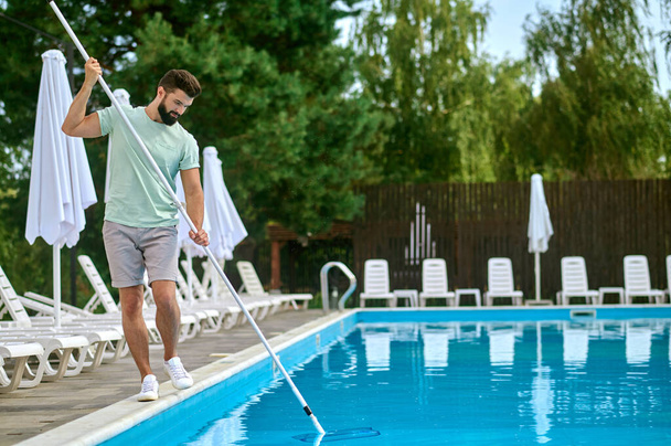 Une personne de service nettoie la piscine et a l'air occupé - Photo, image