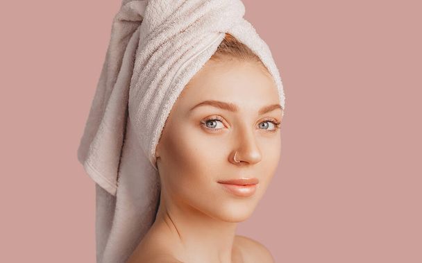 Beautiful sensual young girl with clean skin on a pink background with a mockup. Topless woman in a towel. The concept of spa treatments, natural beauty and care, youth, cream and mask, freshness - Zdjęcie, obraz