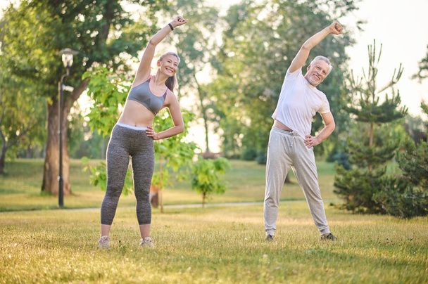 A mature couple exercising in the park - Фото, изображение