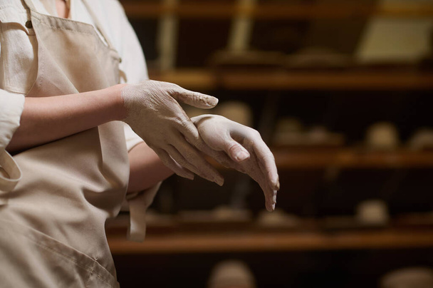 Κοντινό πλάνο των γυναικείων αγγειοπλαστών χέρια σε πηλό - Φωτογραφία, εικόνα