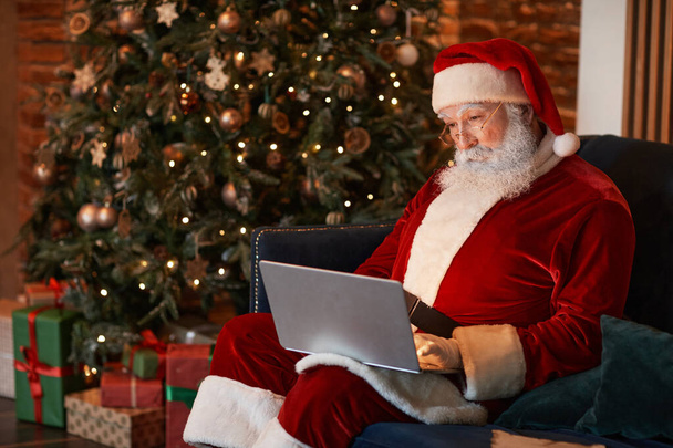 Papá Noel trabajando con portátil
 - Foto, Imagen