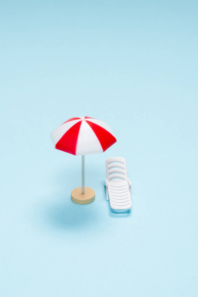 Travel concept. Sun lounger, red umbrella on a blue background. Copy space.  - Фото, зображення