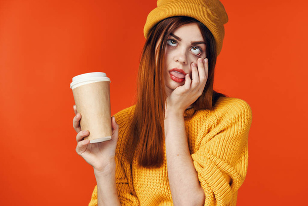 bonita mujer en sombrero amarillo con una taza de bebida caliente en las manos emociones fondo aislado - Foto, Imagen