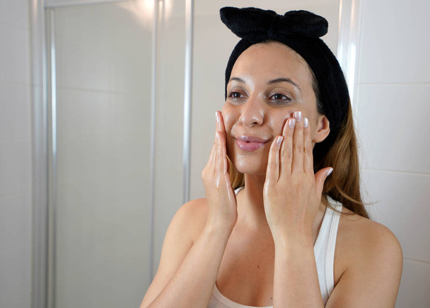 Перший крок - видалення макіяжу очищувальною олією. Красива молода жінка використовує екологічно чисту олію для видалення макіяжу без бавовняної подушечки
. - Фото, зображення