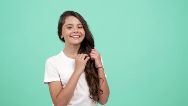 teen dívka dotknout její hladké dlouhé kudrnaté vlasy se šťastnou tváří vyhodit polibek, kadeřnictví koncept - Záběry, video