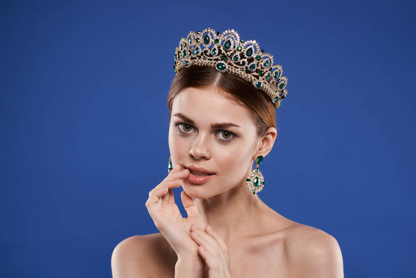 schöne Frau mit einer Krone auf dem Kopf Make-up-Modell Handgeste blauer Hintergrund - Foto, Bild