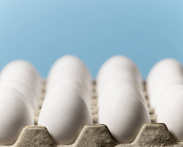 Αυγά κοτόπουλου σε ένα χαρτόνι boxon ένα γαλάζιο φόντο, Ακατέργαστα φρέσκα αυγά κοτόπουλου σε ένα χάρτινο δοχείο, φυσικό προϊόν Eko, Copyspace - Φωτογραφία, εικόνα