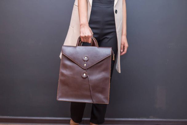 Bruine leren tas in de hand op een vrouw. Unisex tas te koop. - Foto, afbeelding