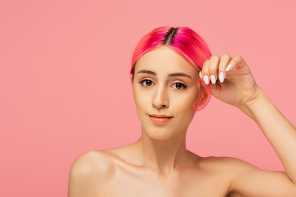 Nuori nainen värikkäitä hiuksia tilalla kosteuttava silmälappu eristetty vaaleanpunainen  - Valokuva, kuva