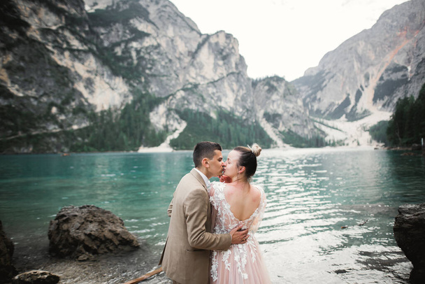 Beautiful modern couple kissing near a lake in the mountains - Foto, afbeelding