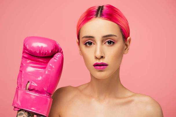 young woman with dyed hair and bright makeup in boxing glove isolated on pink  - 写真・画像