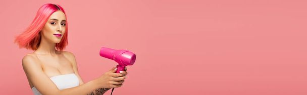 young woman with colorful hair holding hair dryer isolated on pink, banner - Φωτογραφία, εικόνα