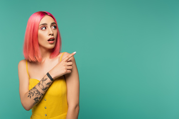 amazed young woman with pink dyed hair poising with finger isolated on turquoise - Foto, afbeelding
