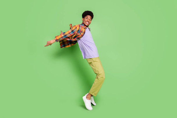 Photo of cute charming dark skin man wear plaid shirt smiling dancing isolated green color background - Foto, Bild