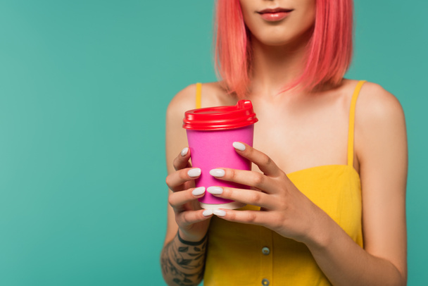 cropped view of young woman with pink dyed hair holding paper cup isolated on blue  - Fotó, kép