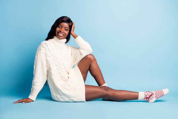 Photo of pretty shiny dark skin lady wear white winter outfit sitting floor having rest isolated blue color background - Φωτογραφία, εικόνα