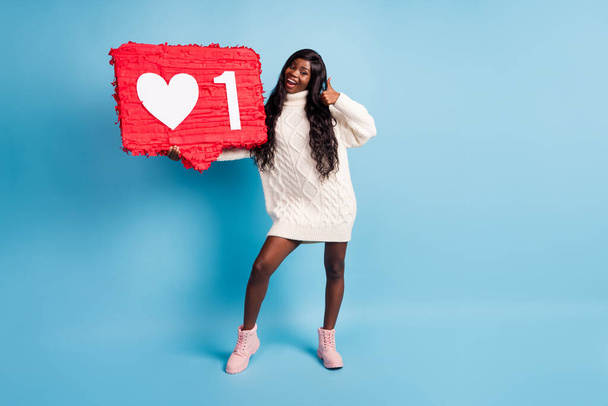 Photo of pretty sweet dark skin lady wear winter outfit holding big click symbol showing thumb up isolated blue color background - Fotoğraf, Görsel