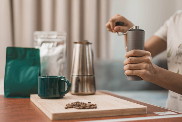 Молода жінка робить каву з обладнанням вдома. Щаслива жінка використовує ручну кавомолку для приготування кави вдома
 - Фото, зображення