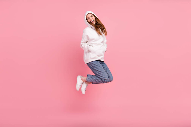 Full length profile photo of millennial lady jump wear hoodie jeans sneakers isolated on pink background - Photo, image