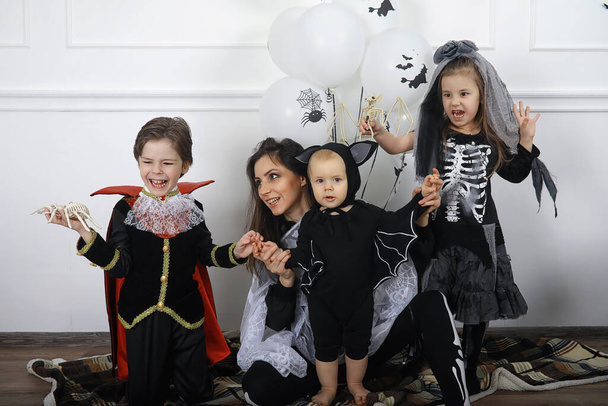 Ευτυχισμένη οικογένεια με παιδιά με στολές μαγισσών και βρικολάκων σε ένα σπίτι στις γιορτές Απόκριες - Φωτογραφία, εικόνα