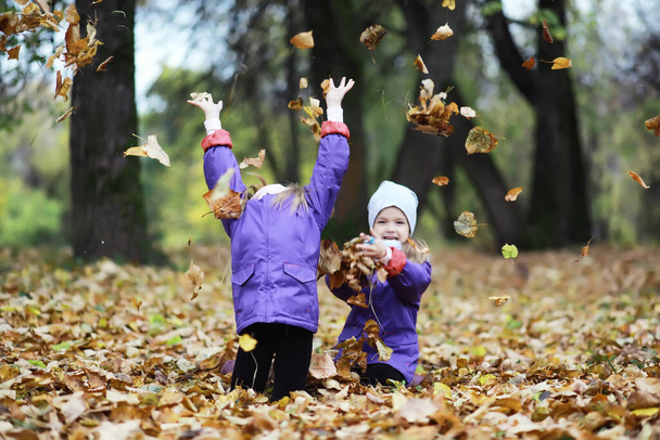 Bambini per una passeggiata nel parco autunnale. Caduta di foglie nel parco. Famiglia. Caduta. Felicità. - Foto, immagini