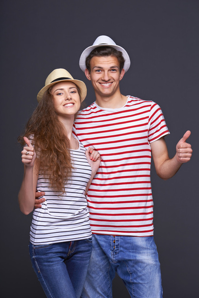 Young casual couple giving thumbs up - 写真・画像