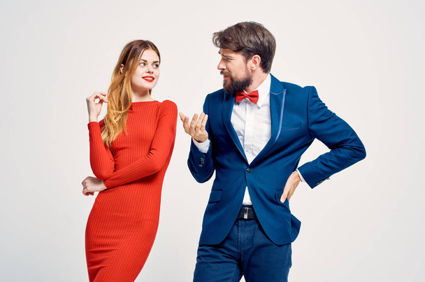 Ein Mann im Anzug neben einer Frau im roten Kleid gestikuliert mit der Hand - Foto, Bild
