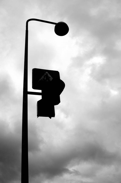 A grayscale shot of a traffic light and a cloudy sky - Zdjęcie, obraz