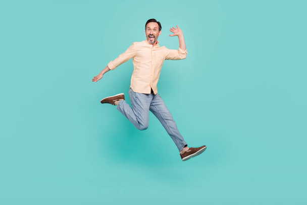 Full size foto van coole leeftijd man jump wear shirt jeans sneakers geïsoleerd op teal kleur achtergrond - Foto, afbeelding