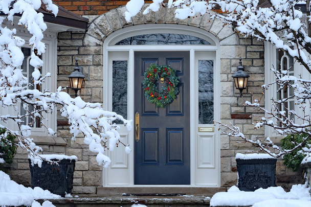 Front door in winter with seasonal wreath, surrounded by snow - Photo, Image
