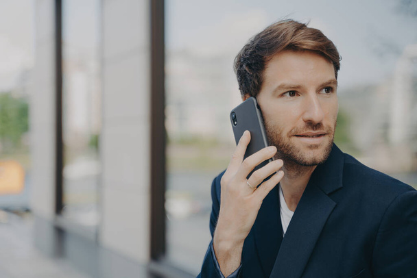 Entrepreneur masculin pensif focalisé sur la distance fait appel à répondre utilise le téléphone mobile - Photo, image