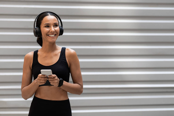 Жінка в спортивному одязі та бездротових навушниках Відпочинок зі смартфоном після тренування на відкритому повітрі
 - Фото, зображення