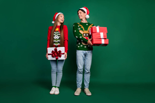 Photo of dream couple hold stack giftbox present wear hat ugly pullover isolated green color background - Foto, afbeelding