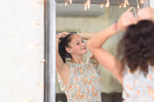 Teen girl looking at mirror and making a ponytail. - Photo, Image