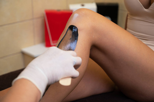 Cosmetologist in beauty clinic performs a epilation procedure - Photo, Image