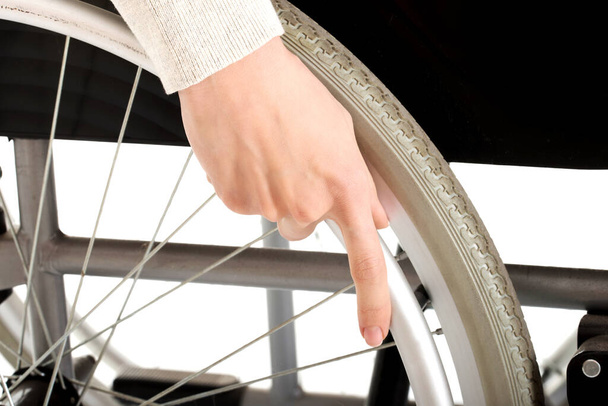 A closeup shot of a woman's hand holding the wheel of a wheelchair - Zdjęcie, obraz