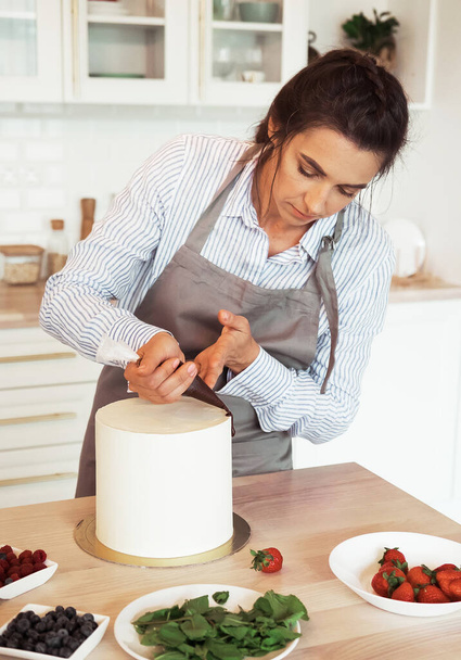 Lifestyle, food, people concept: Pastry chef in the kitchen decorating a cake of chocolate - Foto, afbeelding