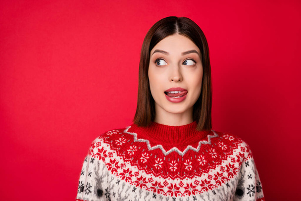 Photo of flirty sweet young lady wear print sweater licking lip looking empty space isolated red color background - Foto, immagini