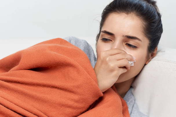 風邪をひいた女性は毛布で覆われたソファの上に横たわっています健康上の問題 - 写真・画像