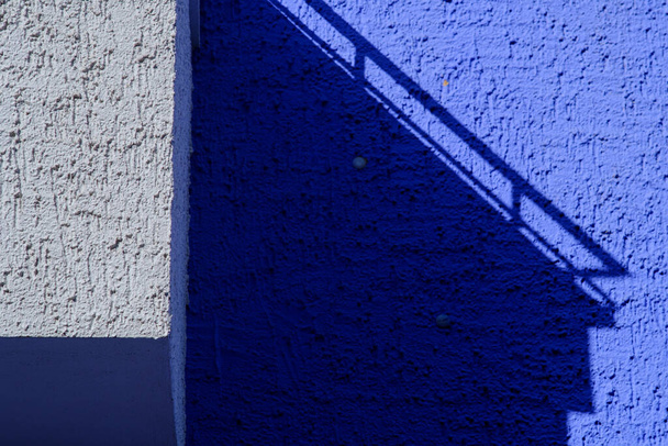 The shadows of a building on the white and purple wall, outdoors during daylight - Fotó, kép