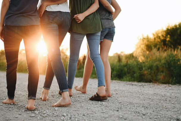 A back view of a group of female friends hugging and walking outdoors on a sunny day - Foto, afbeelding