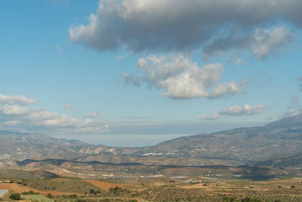 Güney İspanya 'nın dağlık arazisi, birkaç badem ve zeytin ağacı ekini, vadiler, gökyüzü bulutlu. - Fotoğraf, Görsel