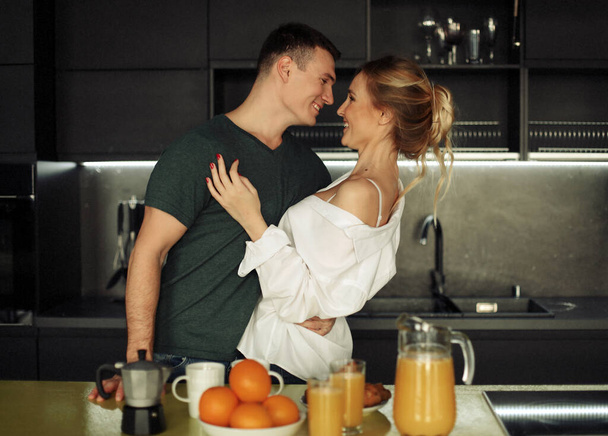Lovely young couple standing and hugging on a kitchen at home - Valokuva, kuva